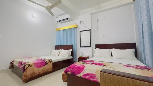 een slaapkamer met 2 bedden en een raam bij Hotel City Panthapath in Dhaka
