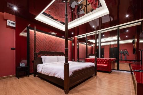 ein Schlafzimmer mit einem Himmelbett und einer roten Wand in der Unterkunft G Boutique Silom Hotel in Bangkok