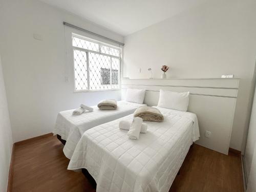 duas camas num quarto branco com toalhas em Apartamento em Belo Horizonte em Belo Horizonte