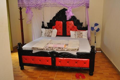 a bedroom with a black and red bed with a canopy at Namulanda Motel in Entebbe