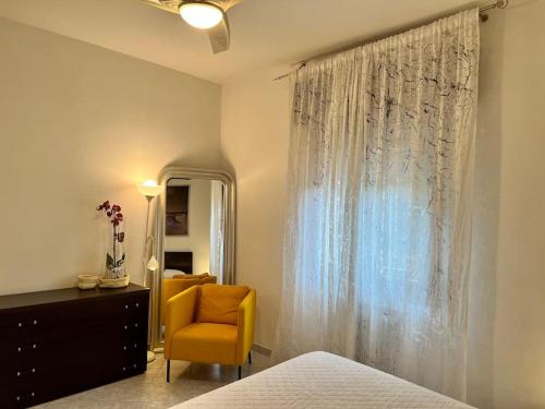 a bedroom with a bed and a yellow chair and a mirror at La tana del Diego in Casalecchio di Reno