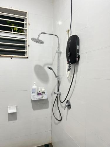 baño con ducha y teléfono en la pared en EMPIRE HOMESTAY PAKA ROOM 3A, en Paka