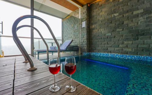 two glasses of wine sitting on a table next to a swimming pool at Anantam Resort & Spa in Kasauli