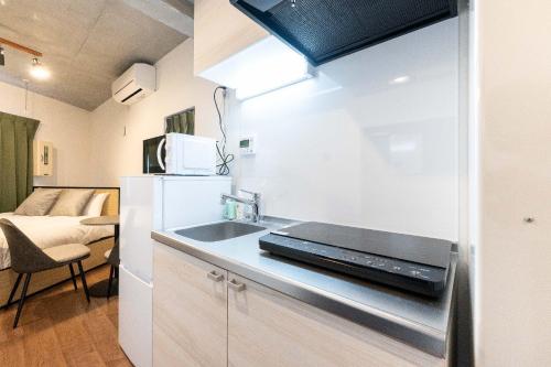 een kleine keuken met een wastafel en een koelkast bij JASPER Waseda in Tokyo