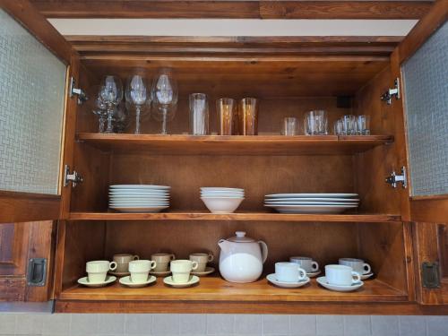 a wooden cabinet filled with dishes and cups and plates at Cozy studio with balcony in 4-star hotel Saint Ivan Rilski, Bansko in Bansko