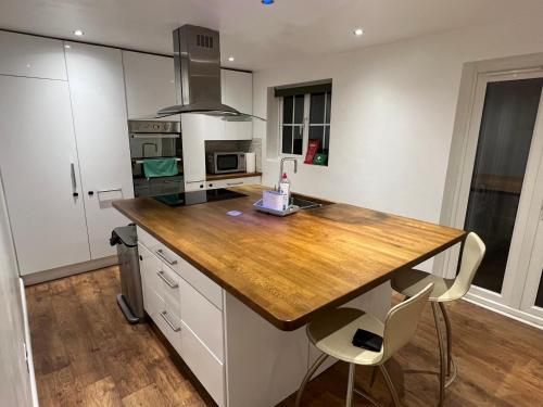 une cuisine avec un comptoir en bois et des armoires blanches dans l'établissement South Cottage, à Hardingstone