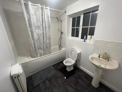 a white bathroom with a toilet and a sink at South Cottage in Hardingstone