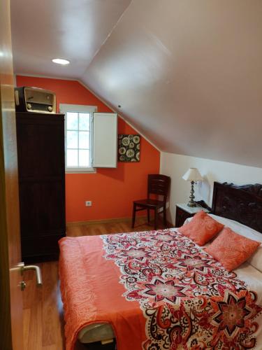 1 dormitorio con 1 cama con paredes de color naranja y ventana en O Faiado, en Crucero