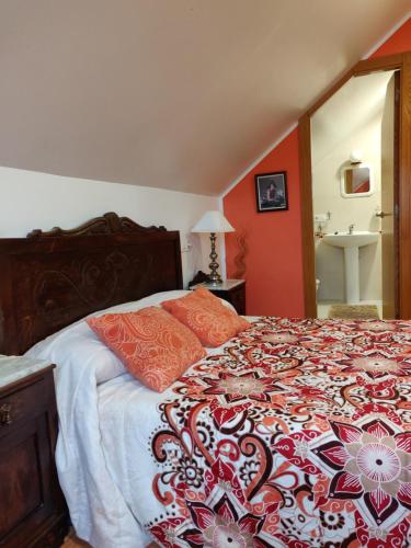 1 dormitorio con 1 cama con manta naranja y blanca en O Faiado, en Crucero