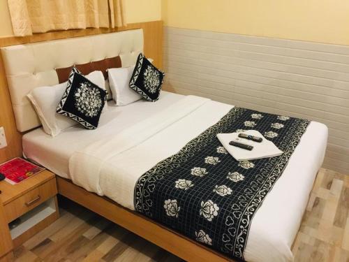 Una cama con almohadas blancas y negras y una bandeja. en Hotel KF Residency en Bombay