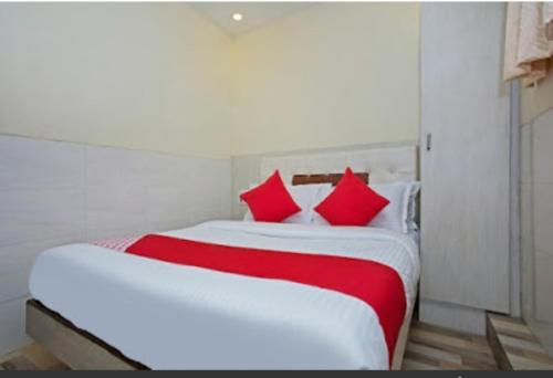 a bedroom with a large white bed with red pillows at Hotel KF Residency in Mumbai