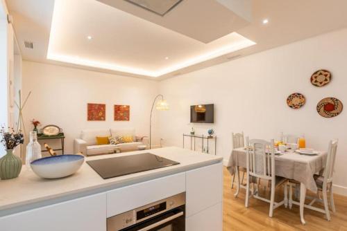 Magno Apartments Casa del Correo Mayor I في إشبيلية: مطبخ وغرفة طعام بجدران بيضاء وطاولة
