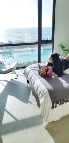 a woman laying on a bed with a laptop at Luxury Beachfront Condo in Rosarito Pool & Jacuzzi in Rosarito