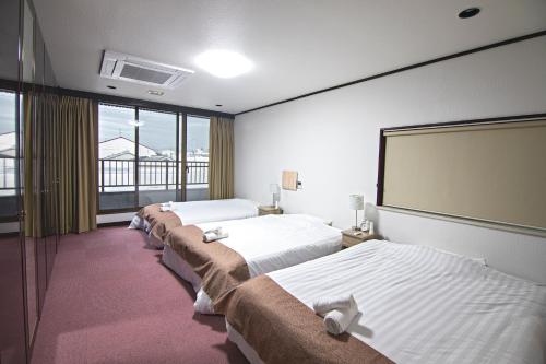 a row of beds in a room with a large screen at -旅time 今里パーク- 最大10人宿泊 今里駅 小路駅に近く 広いキッチン 今里エリア交通便利 in Osaka