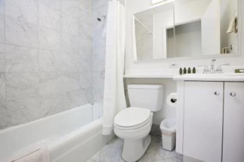 a white bathroom with a toilet and a shower at Beautiful 3 BR Apartment in Manhattan in New York