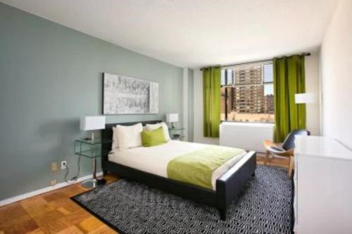 a bedroom with a bed and a window with green curtains at Beautiful 3 BR Apartment in Manhattan in New York