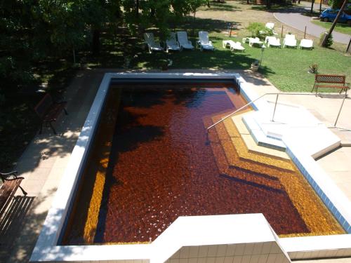a swimming pool with red water in a park at Árnyas Thermal Camping és Üdülőpark in Püspökladány