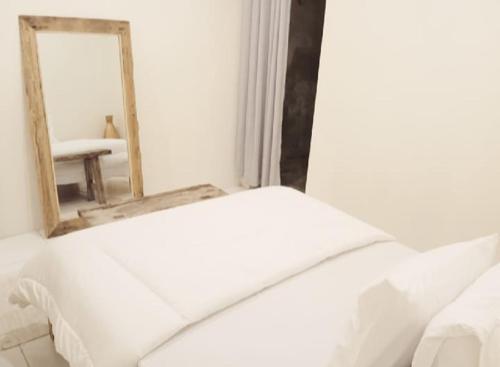 a bedroom with a white bed and a mirror at Classic Local House Grenceng in Denpasar