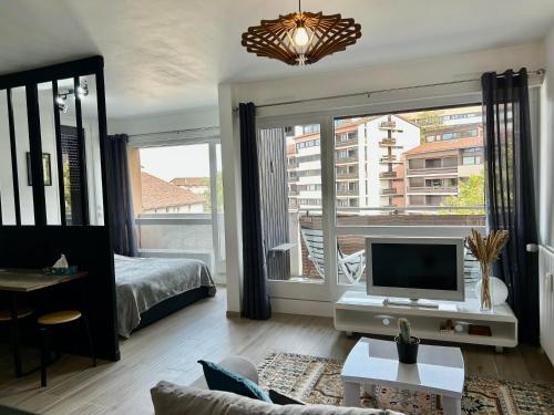 un salon avec une télévision et une grande fenêtre dans l'établissement Studio centre-ville, proche des thermes, à Thonon-les-Bains