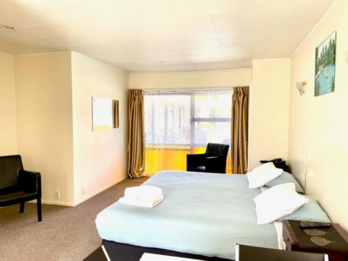 um quarto de hotel com uma cama e uma janela em Dukes Midway Lodge em Auckland