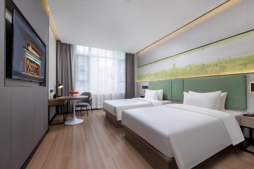 広州市にあるFeili International Hotelのベッド2台とテレビが備わるホテルルームです。