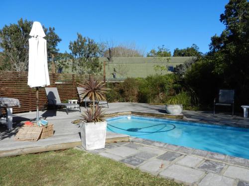 una piscina con terraza y sombrilla en Tsitsikhaya Lodge, en Stormsrivier
