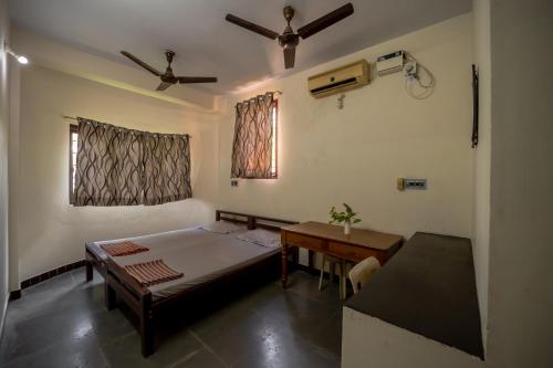 Schlafzimmer mit einem Bett, einem Tisch und einem Fenster in der Unterkunft Sacar Guest House in Puducherry