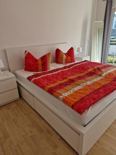 a bedroom with a bed with red and orange pillows at Ferienwohnung Rosenblüte in Neustadt an der Weinstraße