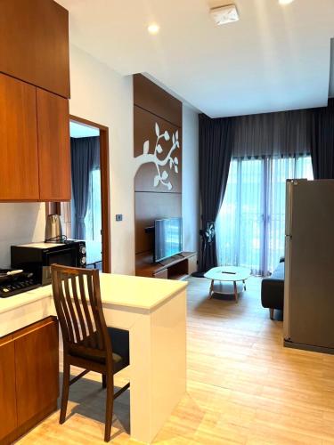 a kitchen and living room with a table and a chair at Tajh Pool Villas in Chalong 