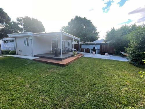 a small white house with a grass yard at Inner City Boutique Home. Pet and Family Friendly! in Canberra