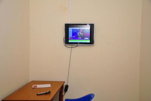 a tv on a wall in a room with a table at Namulanda Motel in Entebbe