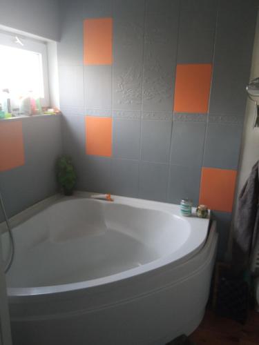 La salle de bains est pourvue d'une baignoire et de carrelage gris et orange. dans l'établissement chambre dans maison coquette et accueillante, à Dunkerque
