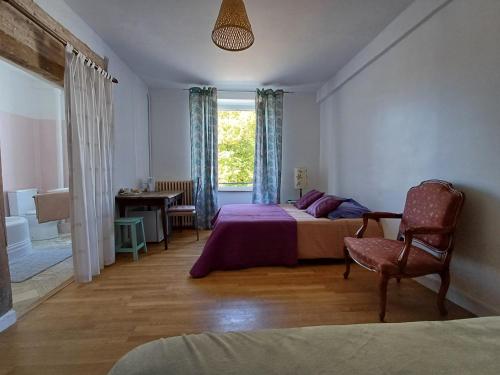 a bedroom with a bed and a chair and a window at Maison Violette en Berry in Aigurande