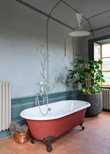 a red bath tub in a room with plants at Vigne di Fagnano 1709 Eco Relais in Santo Stefano Belbo