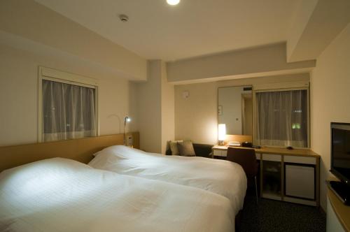 una camera d'albergo con letto bianco e TV di Hotel Sunflex Kagoshima a Kagoshima