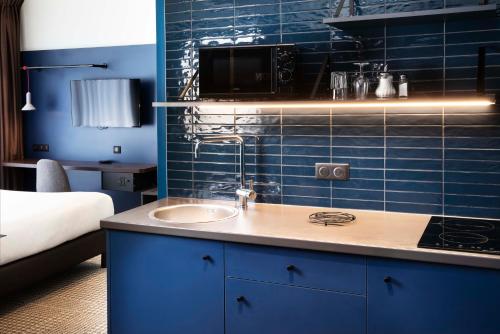 baño con lavabo y pared de azulejos azules en Hotel Le Bugatti, en Molsheim