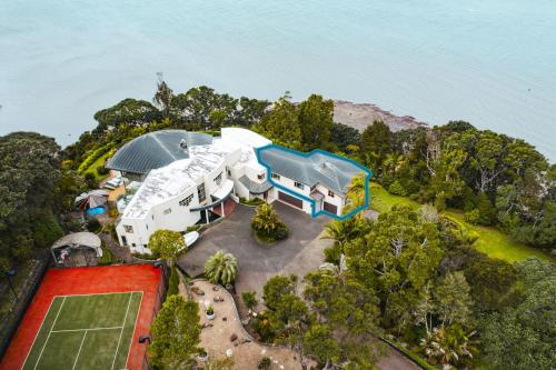 an aerial view of a house on a hill next to the water at Beachside Luxury - Laingholm Holiday Apartment in Titirangi