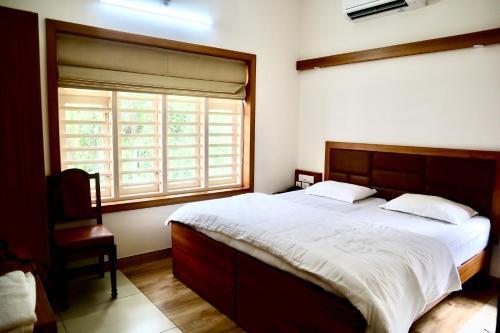 a bedroom with a large bed and a window at Choice Beach House in Kannur