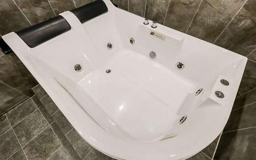 Seosan Hotel November في Seosan: حوض استحمام كبير أبيض في الحمام