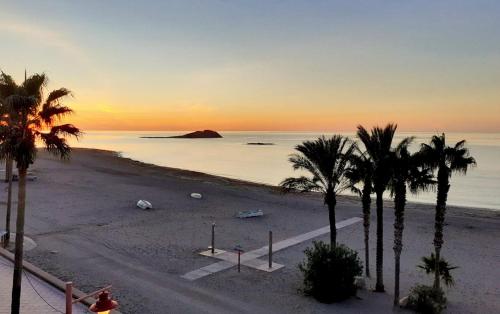 una playa con palmeras y el océano al atardecer en Alboran hotel, en Carboneras