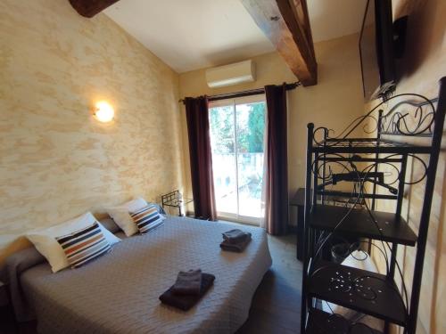 ein Schlafzimmer mit einem Bett in einem Zimmer mit einem Fenster in der Unterkunft Logis Hotel Restaurant L'Esquielle in Saint-Géniès-de-Malgoirès
