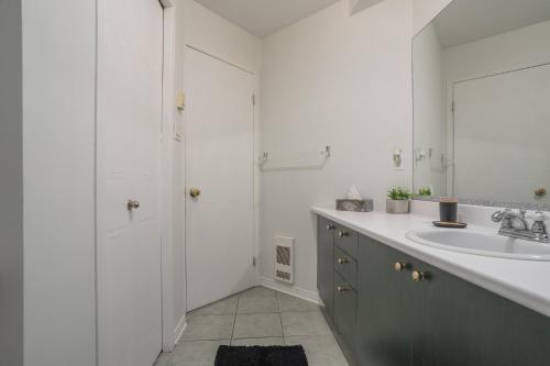 La salle de bains blanche est pourvue d'un lavabo et d'un miroir. dans l'établissement Amazing 4-Bedrooms MONTREAL, à Montréal