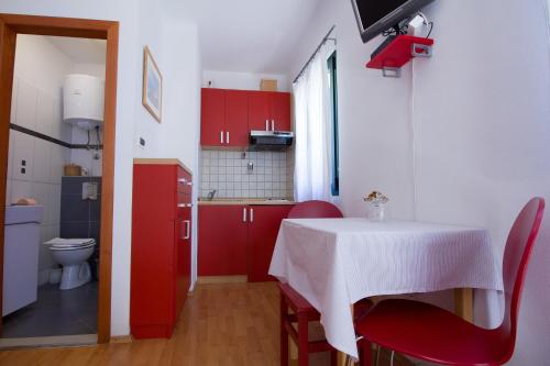 a small kitchen with a table and red cabinets at Apartments Baška in Baška