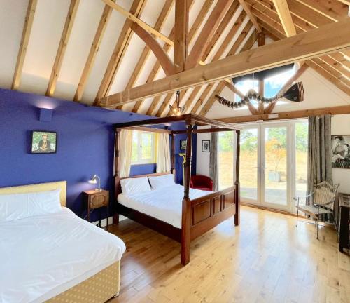 a bedroom with two beds and a blue wall at The Mill House on the Brooks South Downs West Sussex Sleeps 15 in Hardham