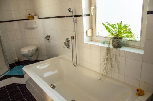 a bathroom with a tub and a toilet and a window at Private doublebed Room with balcony in shared house in Dornbirn