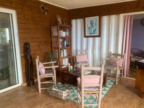 ein Wohnzimmer mit einem Tisch, Stühlen und einem Bücherregal in der Unterkunft Là Haut-Lé Beau in Le Lambert