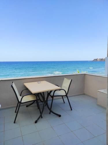 a table and chairs on a balcony overlooking the ocean at Filoxenia Beach Hotel in Rethymno Town