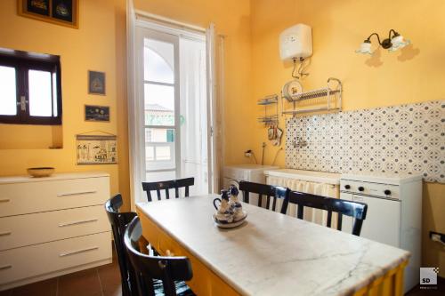 uma cozinha com paredes amarelas e uma mesa e cadeiras em Appartamento La dolce vita em Tropea