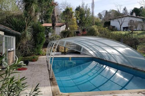 einen Pool mit einem Gewächshaus aus Glas neben einem Haus in der Unterkunft Grand T2 au calme, entre mer et montagne in Arbonne