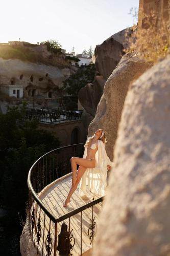 a woman in a white dress sitting on a balcony at Cappadocia Gamirasu Cave Hotel in Urgup